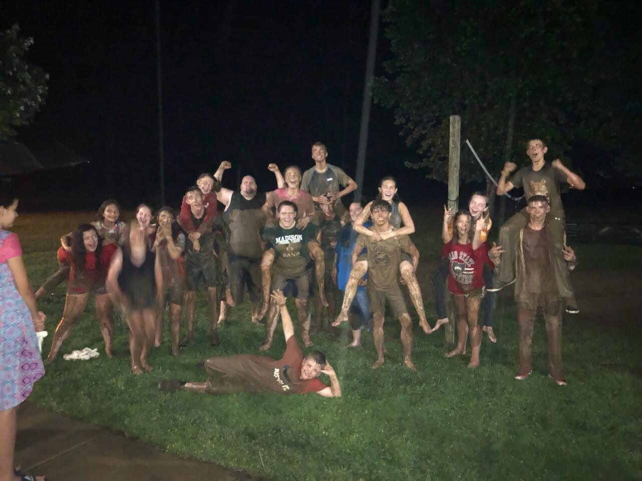 Campers covered in mud cheering after an evening mud game
