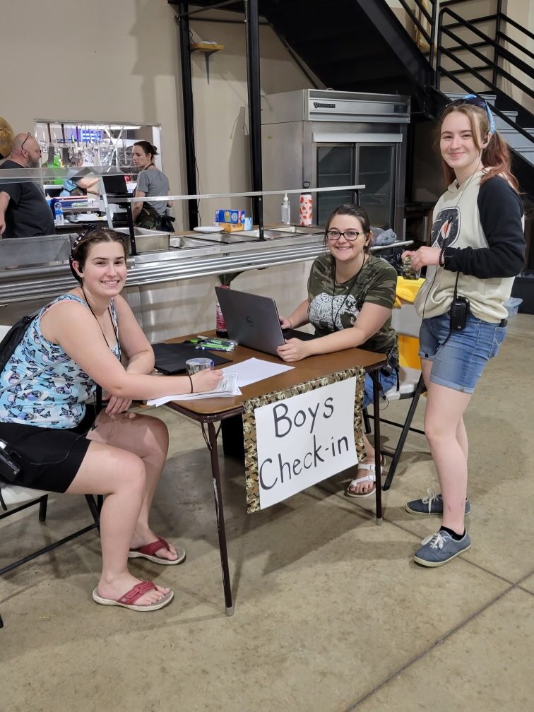Camp staff smiling at the boys check-in table