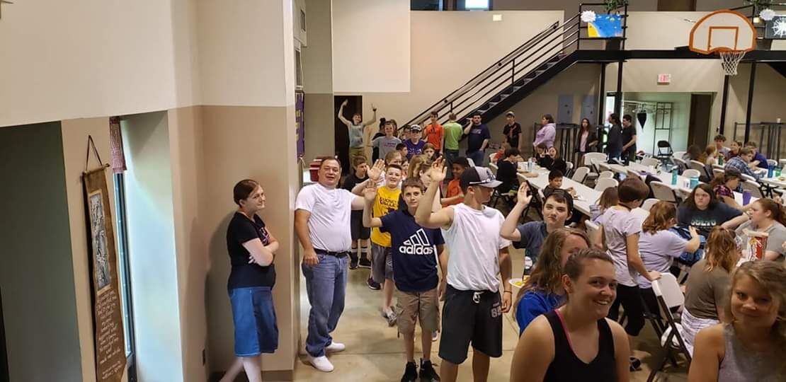 Campers waving in the dining hall during a meal