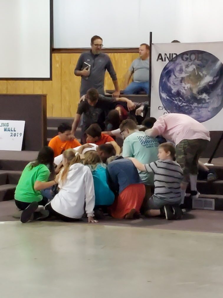 Campers kneeling together in prayer at the altar
