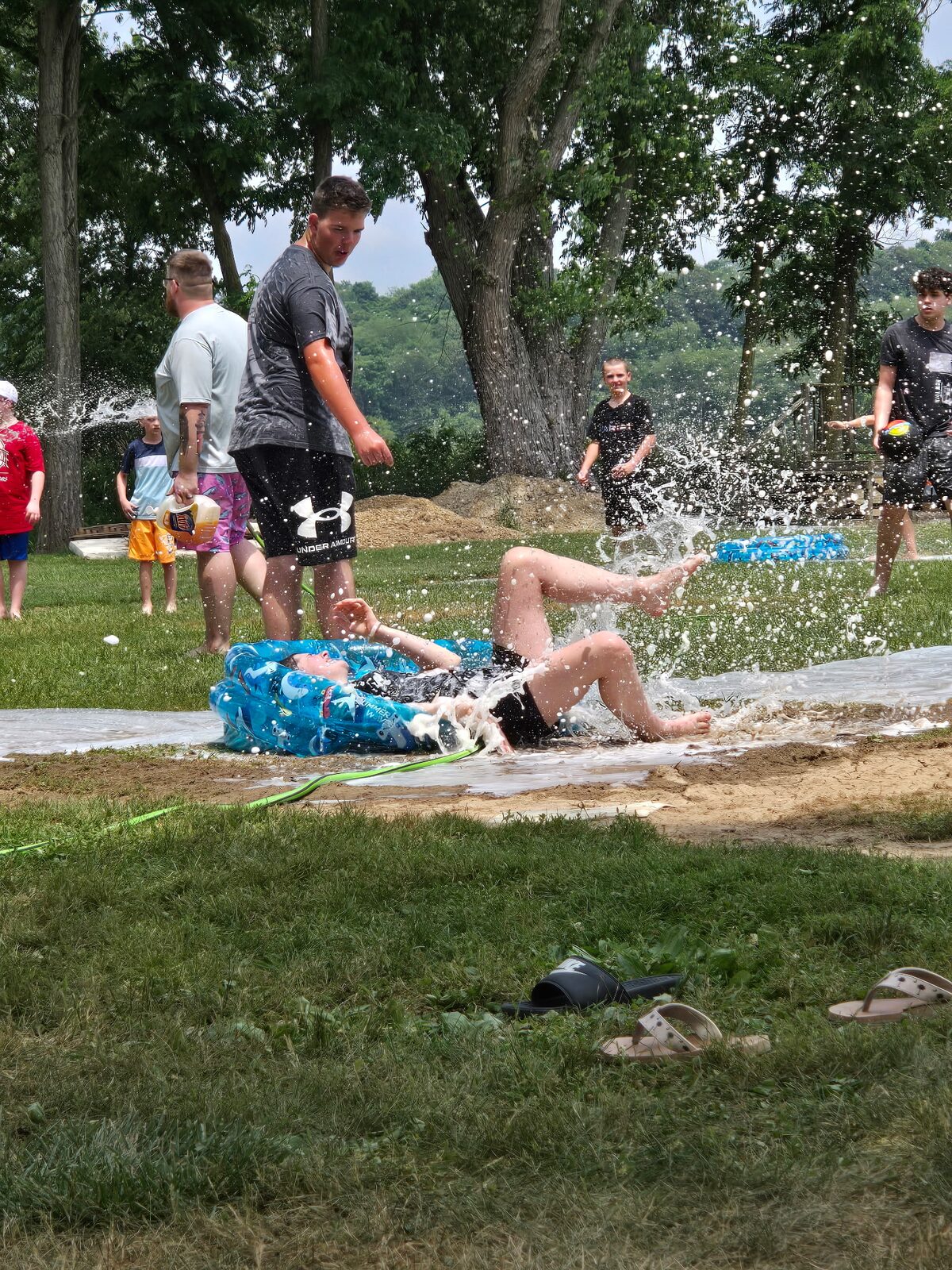 A camper sliding down the slip-and-slide on a summer afternoon