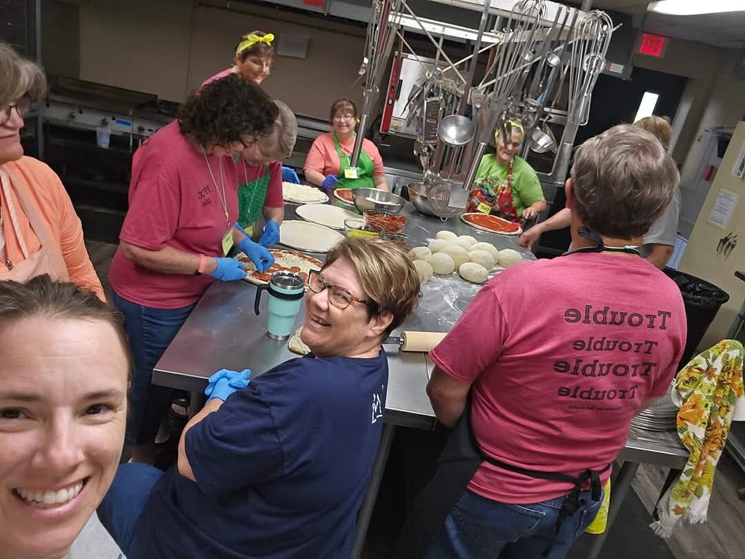Kitchen volunteers preparing pizzas for the camp meal