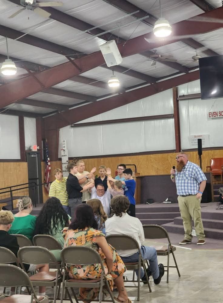 Campers on stage praying over a speaker during a service